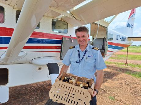 Pilot Jono Pound unloads chicks from his plane at Maridi Airport