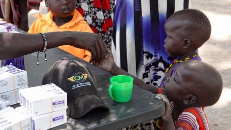 A little boy greets the pharmacist as he waits to receive medicine