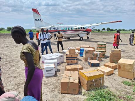MAF aircraft sits on the ground at Akobo airstrip as essential medical and shelter supplies are offloaded for CARE International to set up medical facilities and strengthen critical health services.